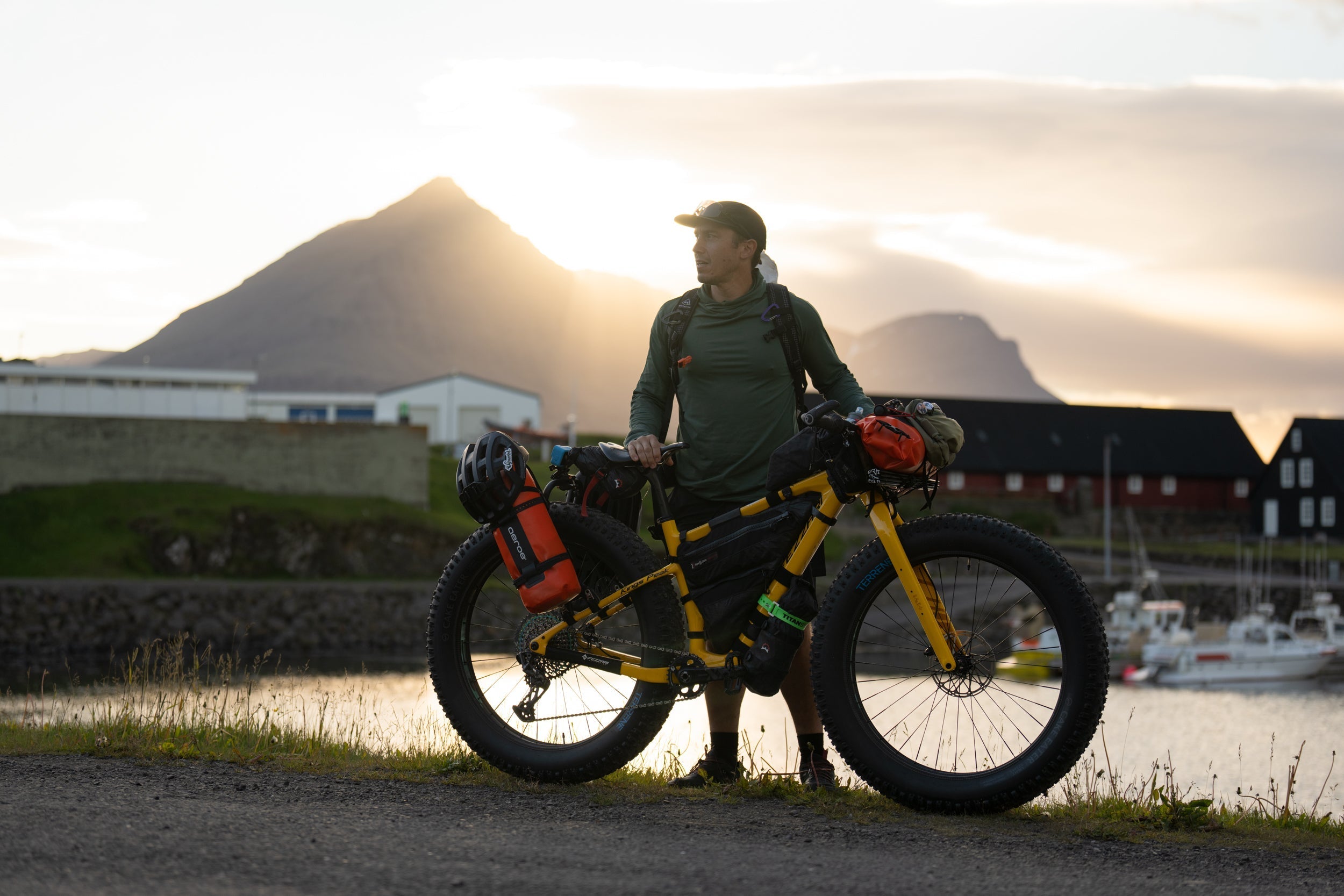 Chris Burkard stands beside a loaded yellow fat-tire bike on Iceland’s South Coast at sunset
