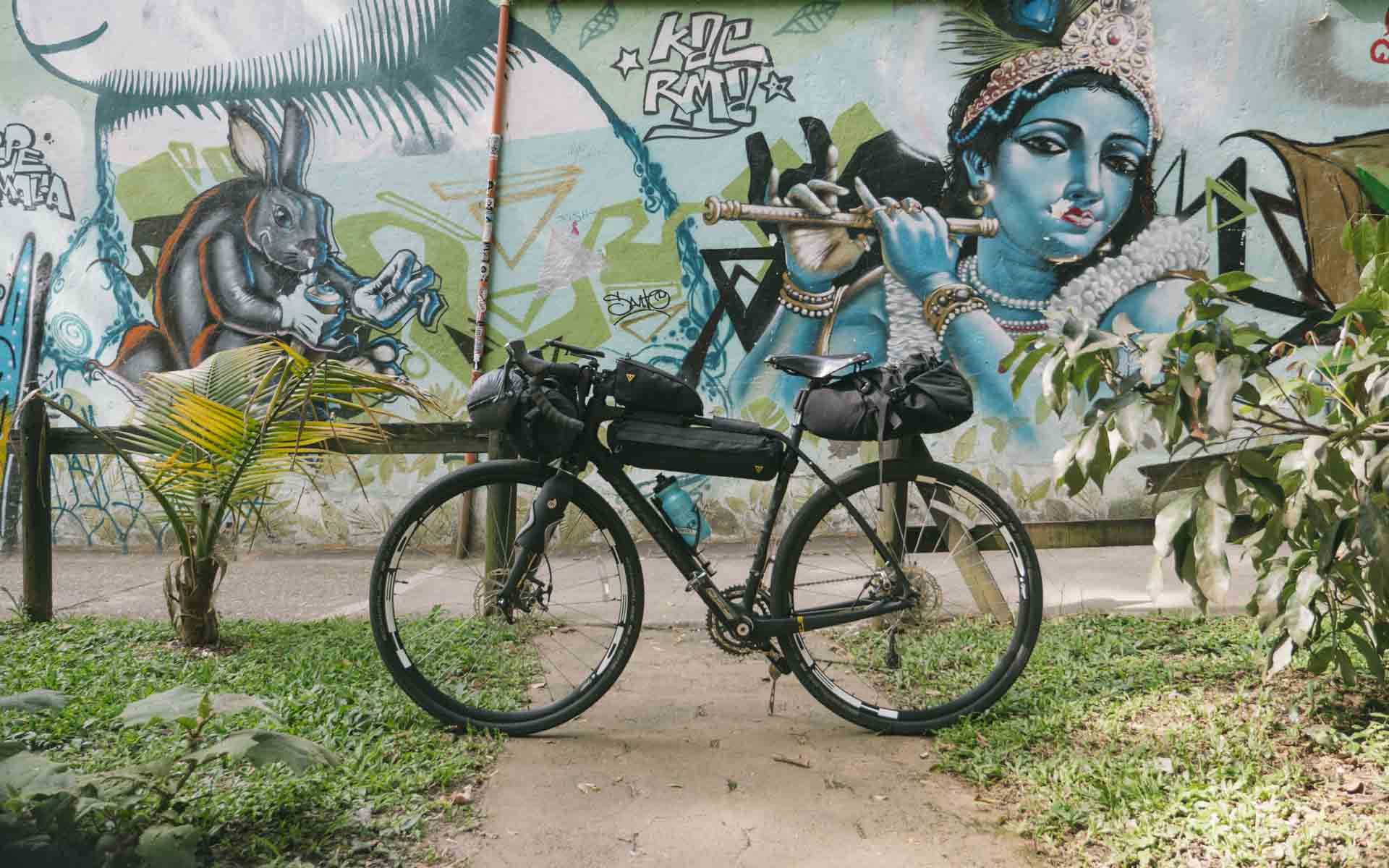 Bikepacking bicycle with bags parked beside a colorful mural