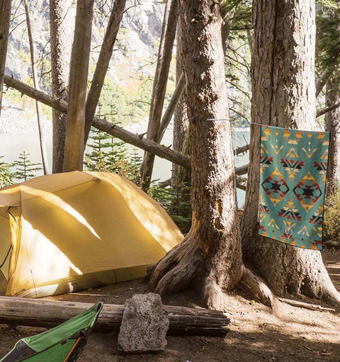 A campground with a tent and a Nomadix towel hanging in the trees.