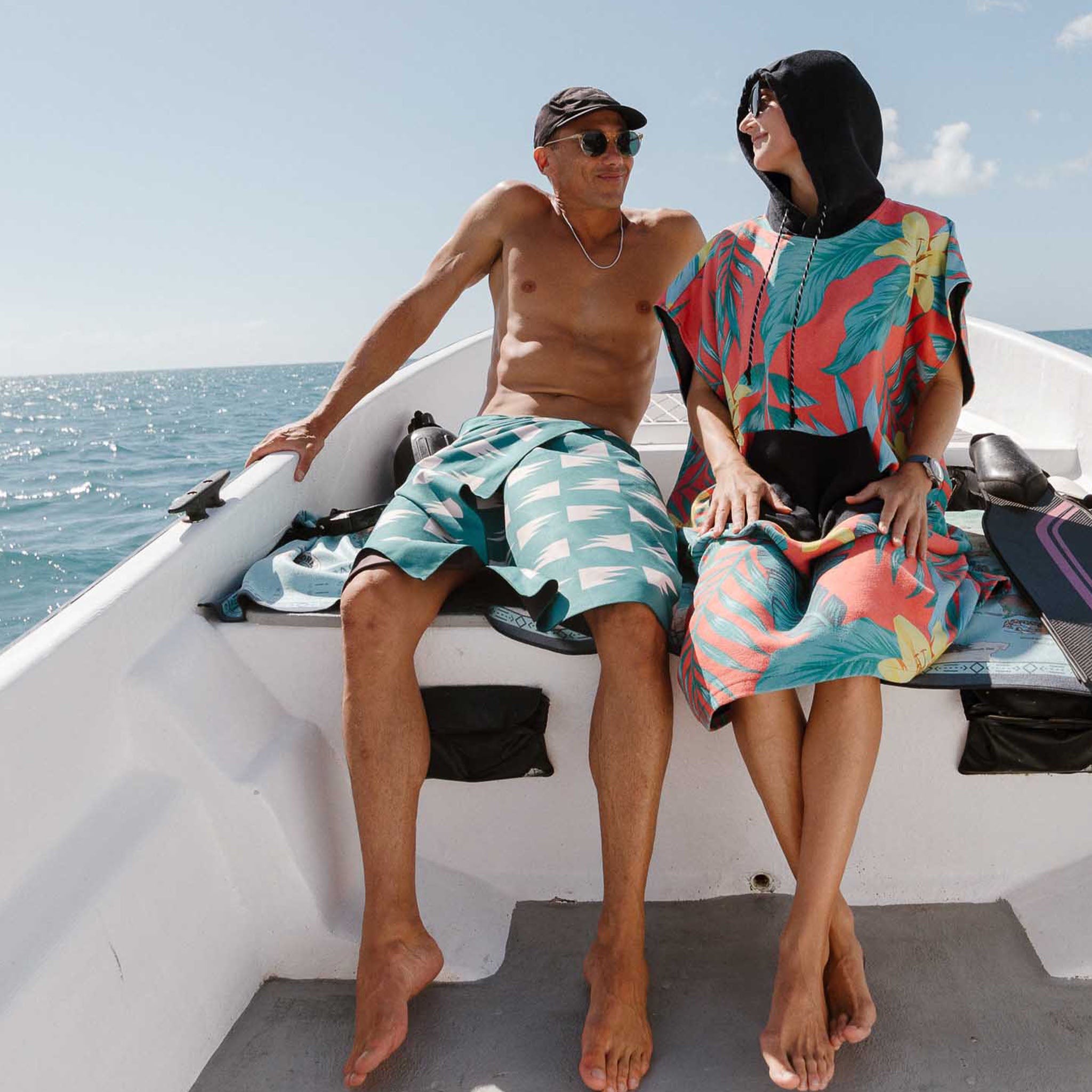 Two people relax on a boat with colorful towels over a sunny ocean