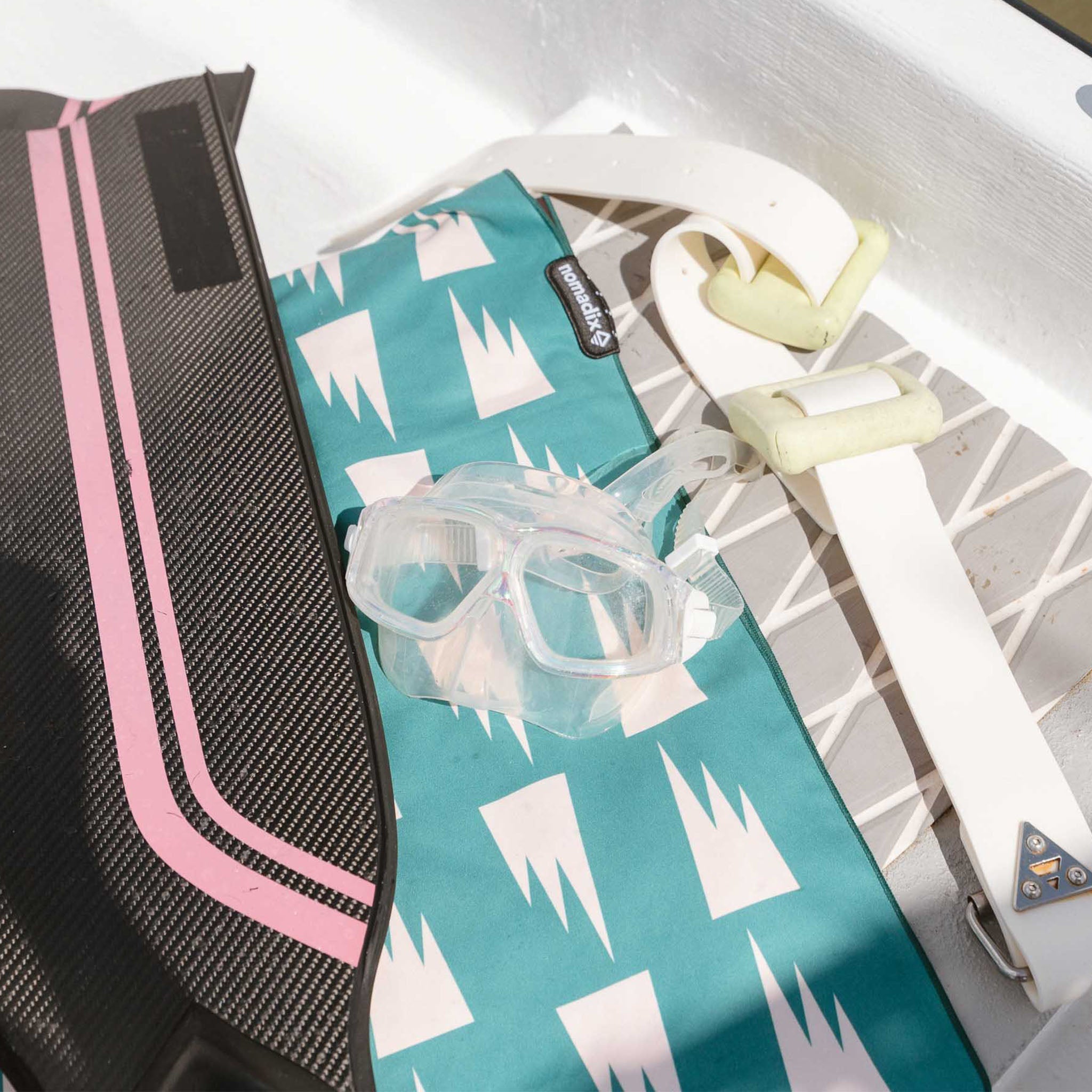 Top view of Nomadix Ultralight Towel in Summit Green showcasing a white geometric pattern with snorkeling gear on a boat deck